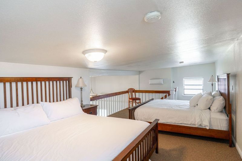 A hotel room with two beds and a balcony.