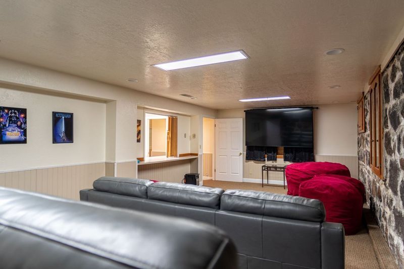 A living room with a couch , chairs and a flat screen tv.