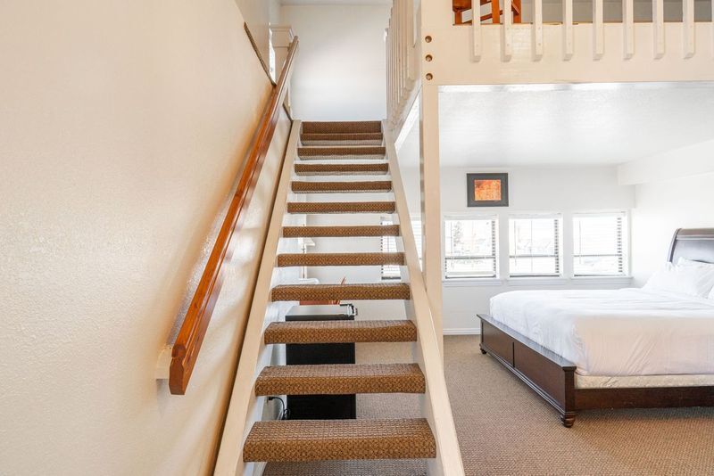 A bedroom with a bed and stairs leading up to it.
