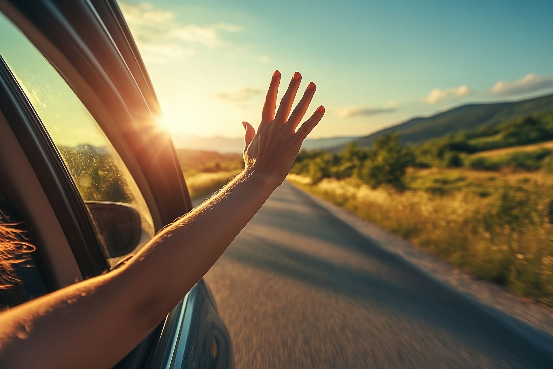 A woman is waving her hand out of a car window.
