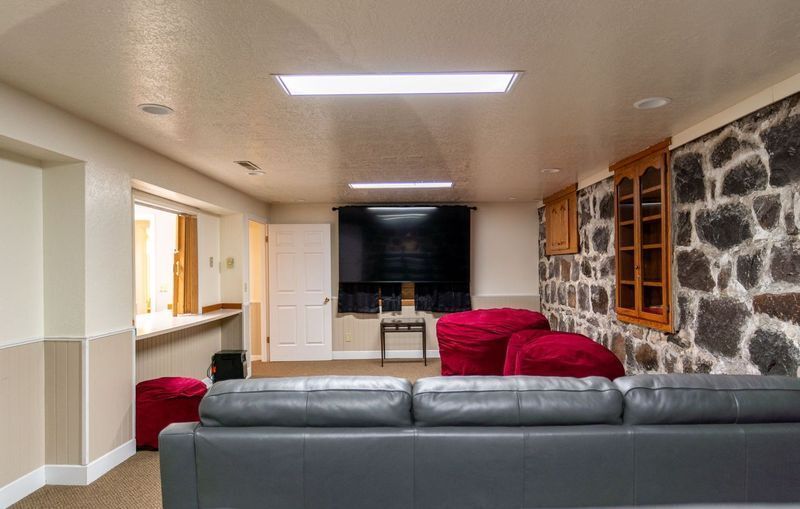 A living room with a couch , ottomans , and a stone wall.