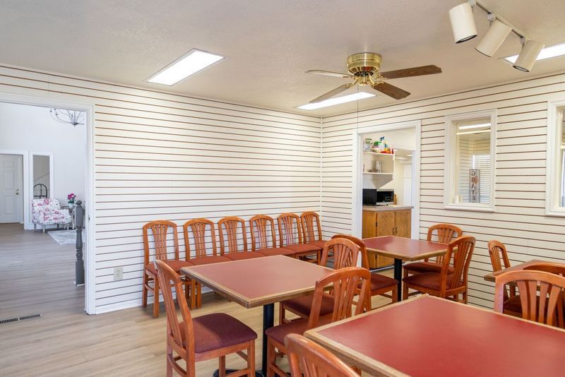 A dining room with red tables and chairs and a ceiling fan.