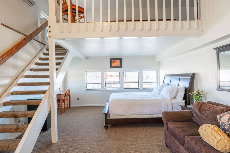 A bedroom with a bed and stairs leading up to it