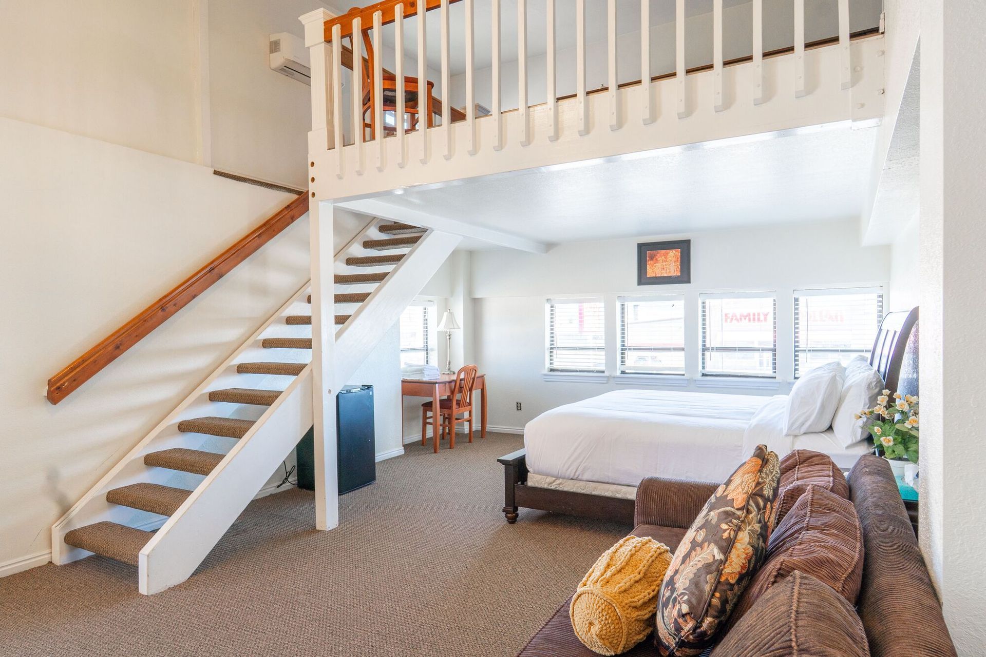 A hotel room with a bed , stairs and a couch.
