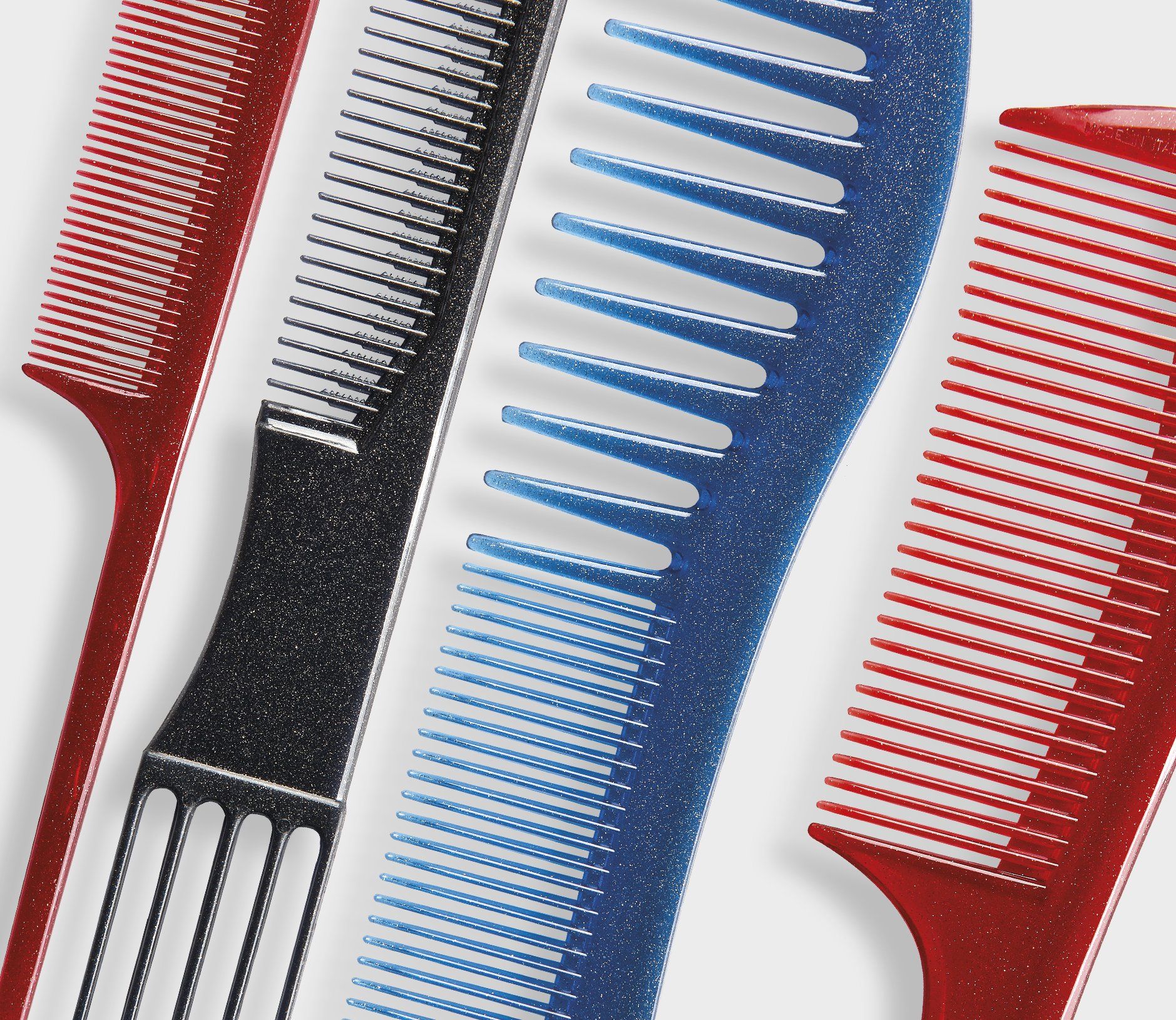 Tre pettini di colore diverso sono allineati su una superficie bianca