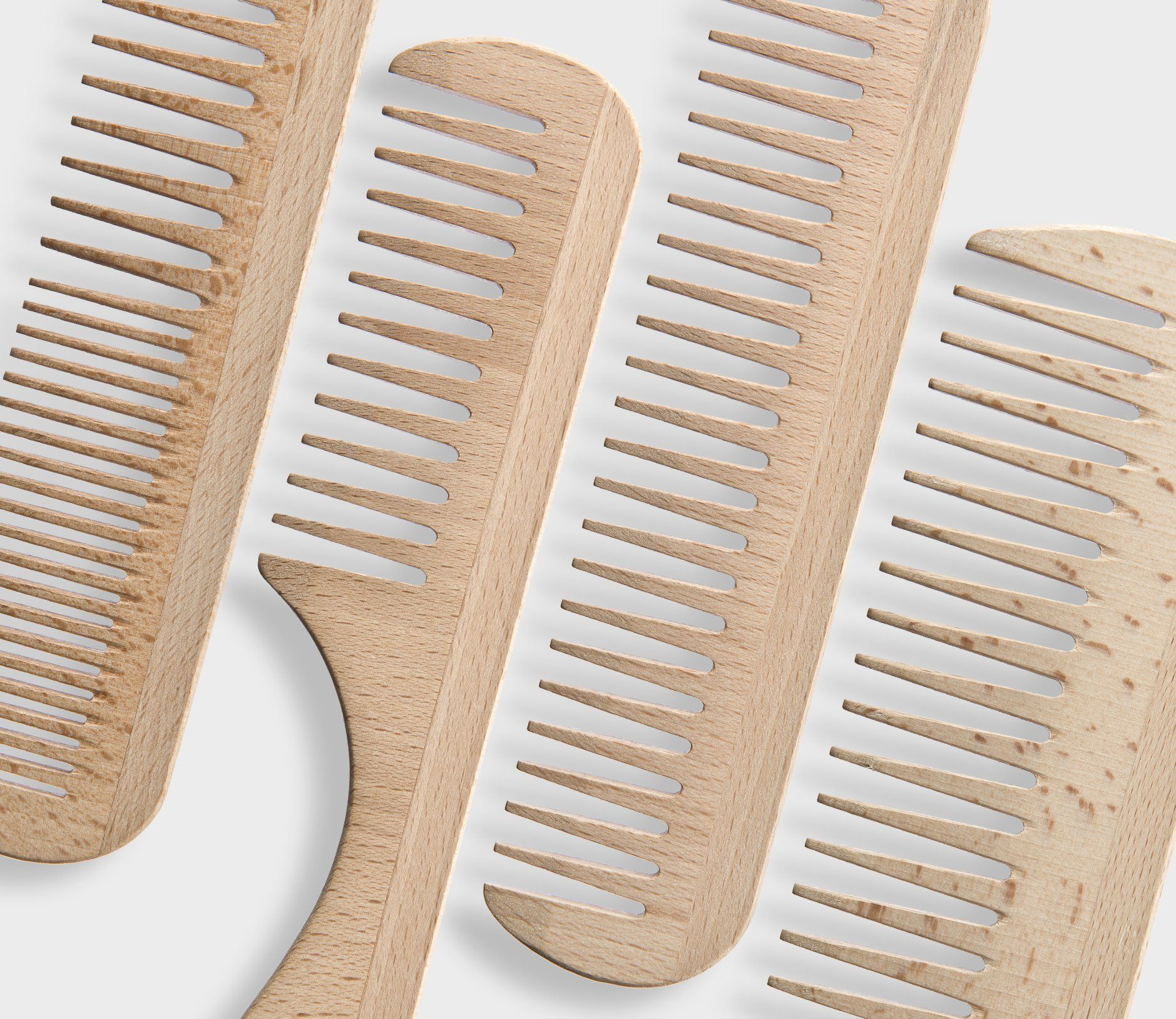 Tre pettini di legno sono allineati su una superficie bianca