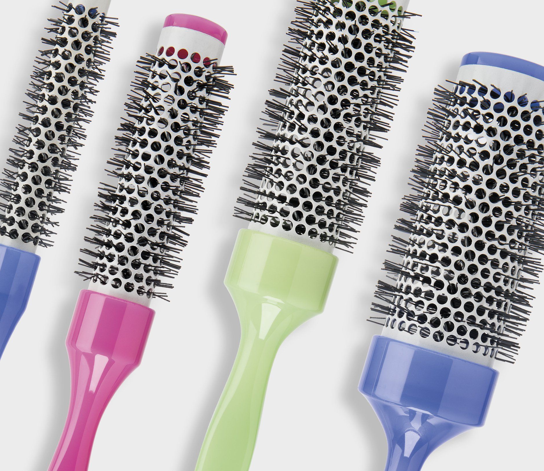 Quattro spazzole per capelli di colore diverso sono allineate in fila