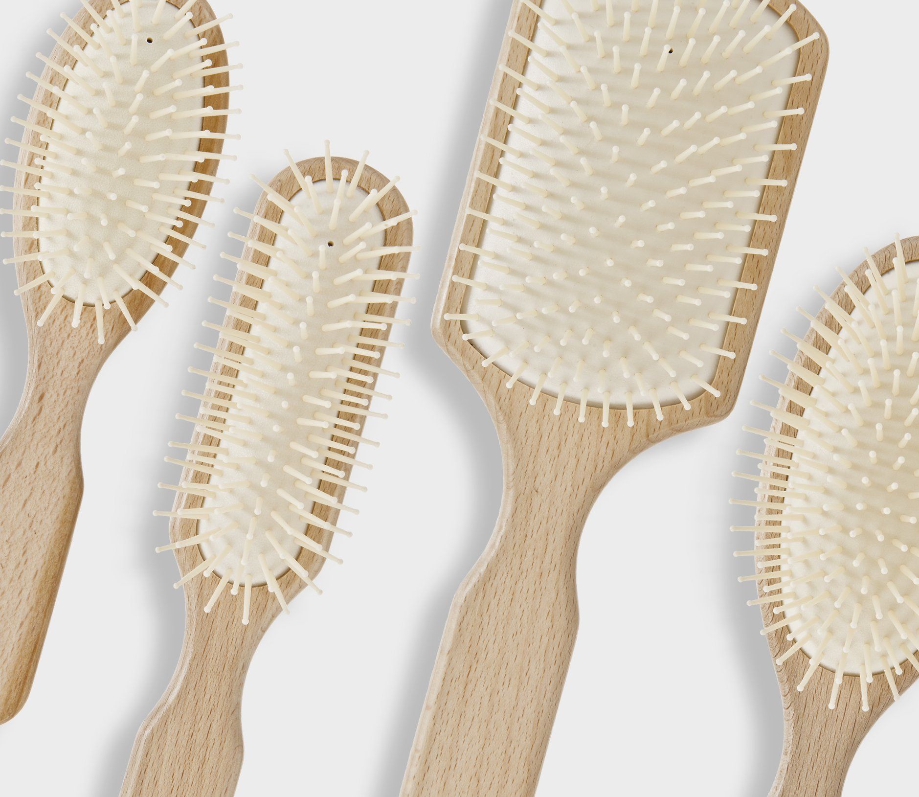 Un gruppo di spazzole per capelli con manici in legno e setole bianche