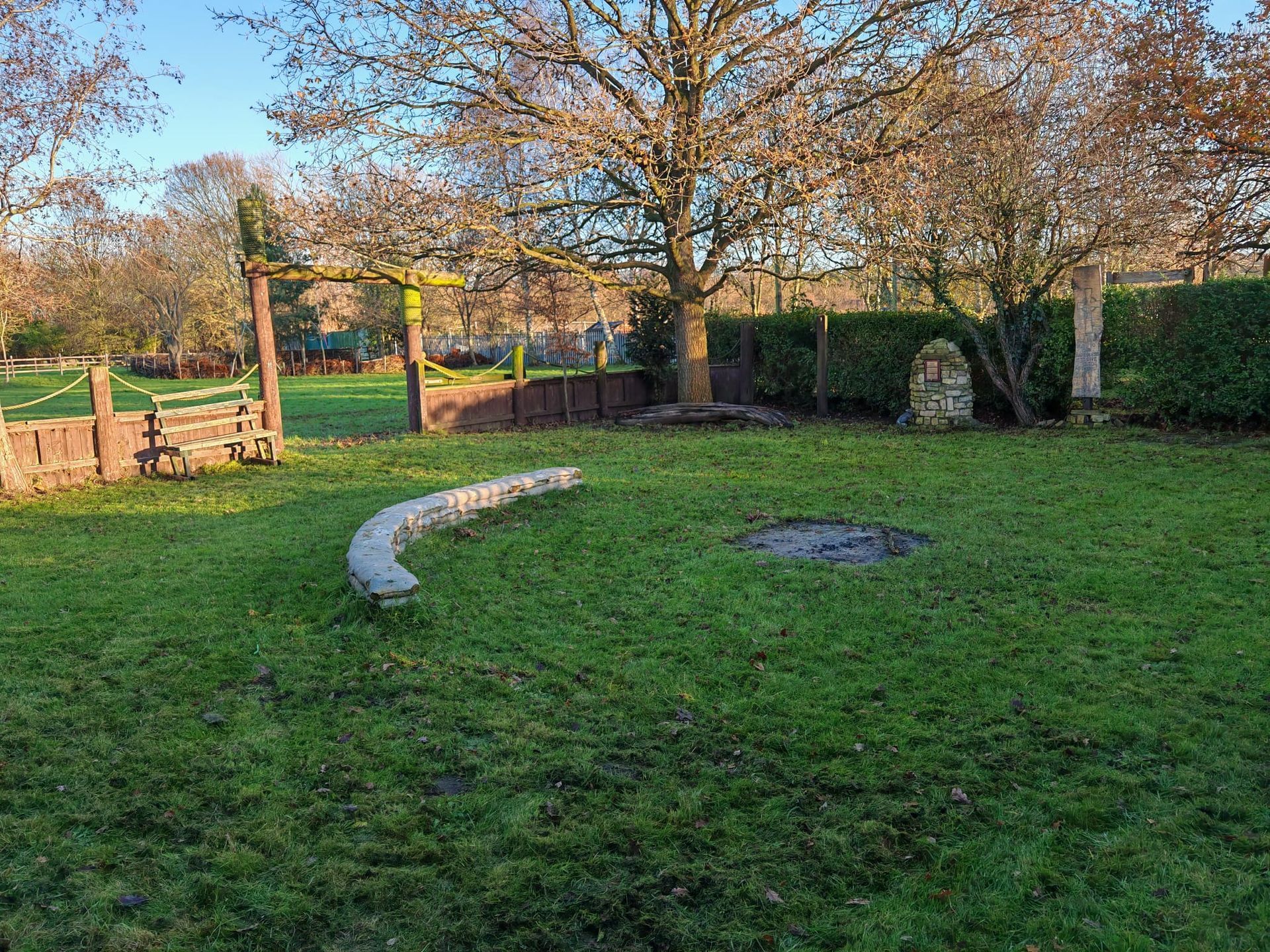 Altham Terrace Scout HQ campfire circle in winter, with winter sun and bare trees surrounding the stone fire pit.