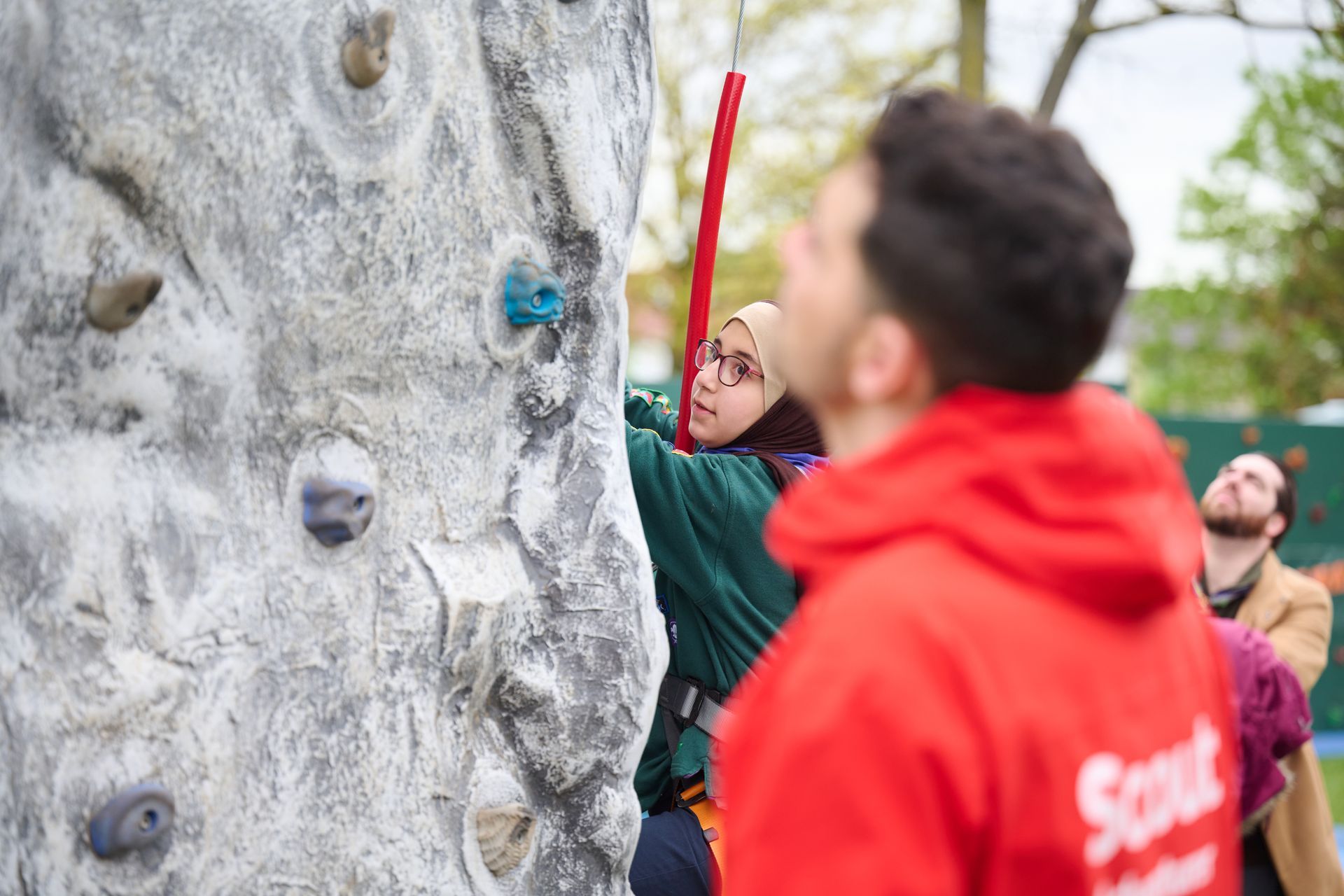 Scout climbing an outdoor wall with leader, highlighting the importance of safety in Scouting.