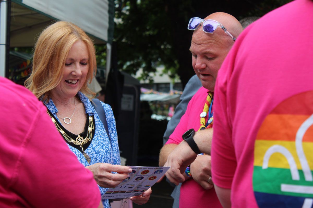 Lee, District Lead Volunteer, chatting with Pride attendees about Scout Pride bingo. District Lead Volunteer Lee talks with Pride attendees about Scout Pride bingo at the Family Zone.