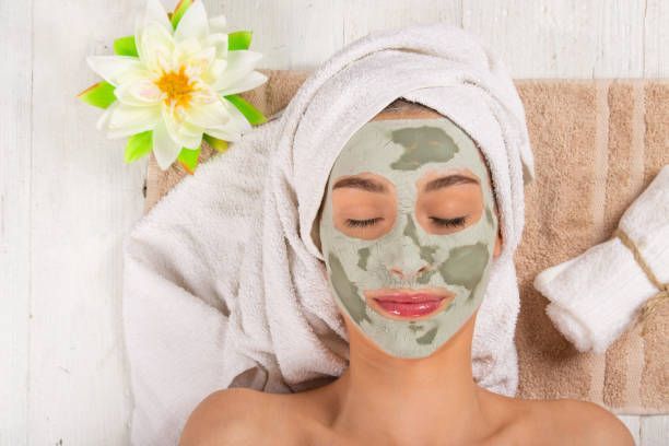 A woman is getting a clay mask on her face at a spa.