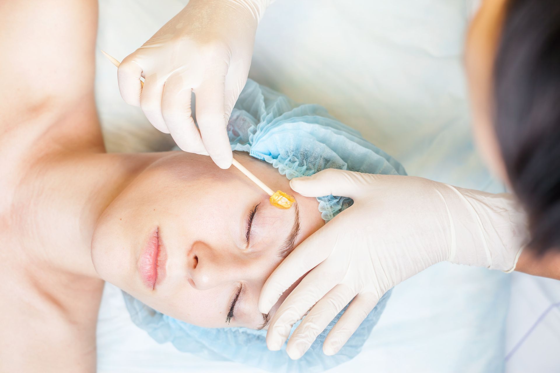 A woman is getting her eyebrows waxed in a beauty salon.
