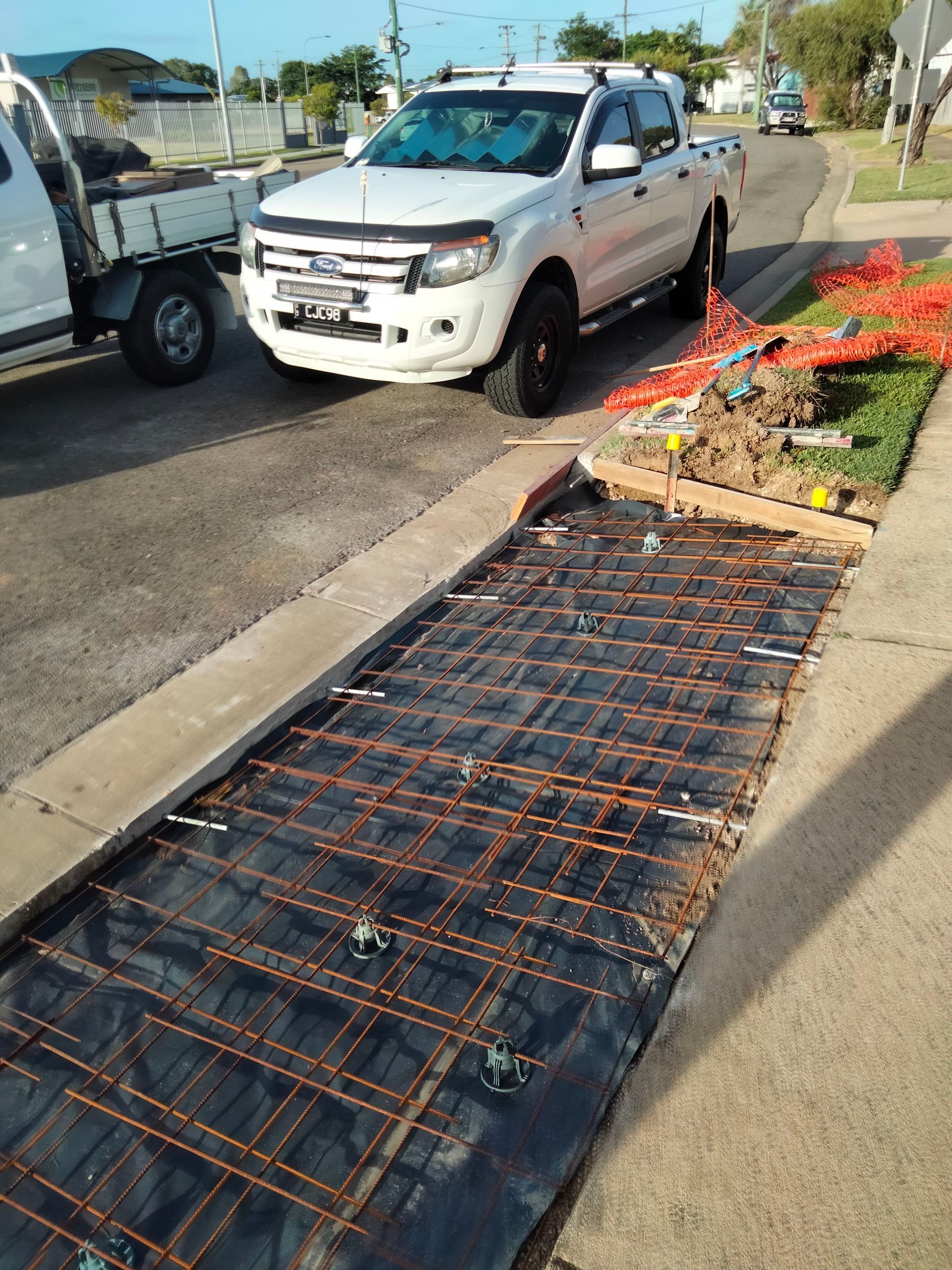 White pickup truck beside a damaged sidewalk ramp with orange netting and debris on the curb — King Reef Concrete in Kurrimine Beach, QLD