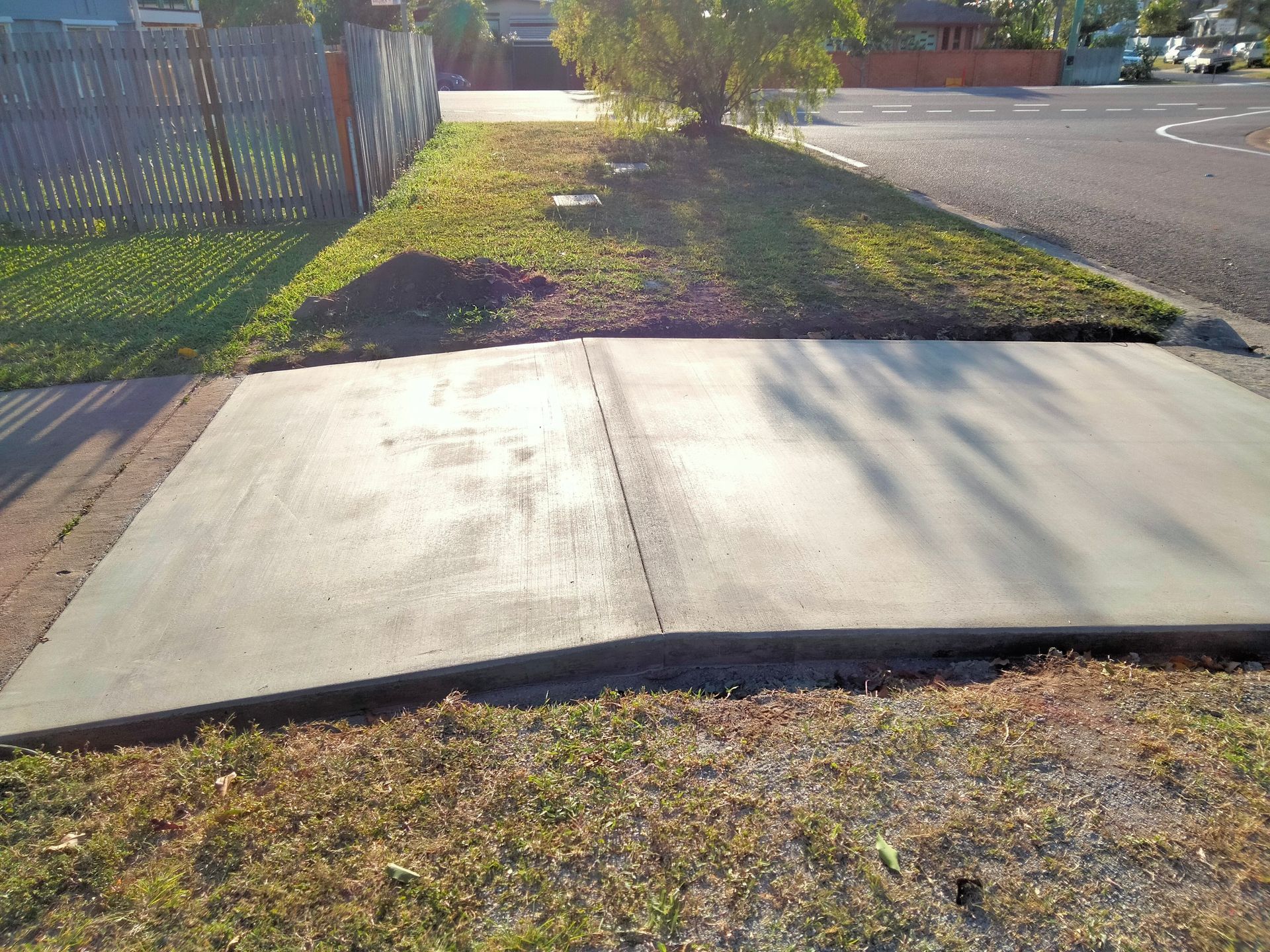 Broken concrete sidewalk ramp beside a grassy curb and road in daylight — King Reef Concrete in Kurrimine Beach, QLD