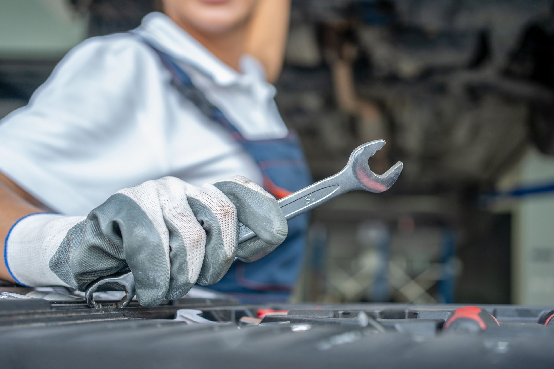 Mechanic holding a wrench while working on a car engine.
