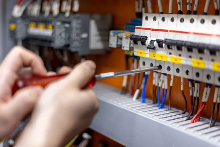 Una persona sta lavorando su una scatola elettrica con un cacciavite.