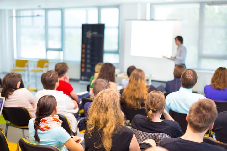 Un gruppo di persone è seduto in un'aula magna e guarda una presentazione.
