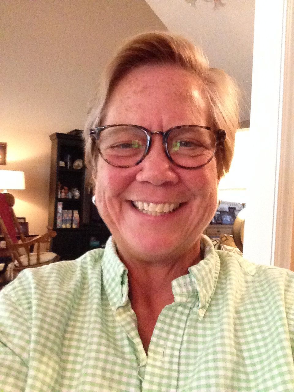 A woman wearing glasses and a green shirt smiles for the camera