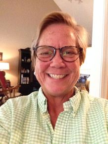 A woman wearing glasses and a green shirt smiles for the camera