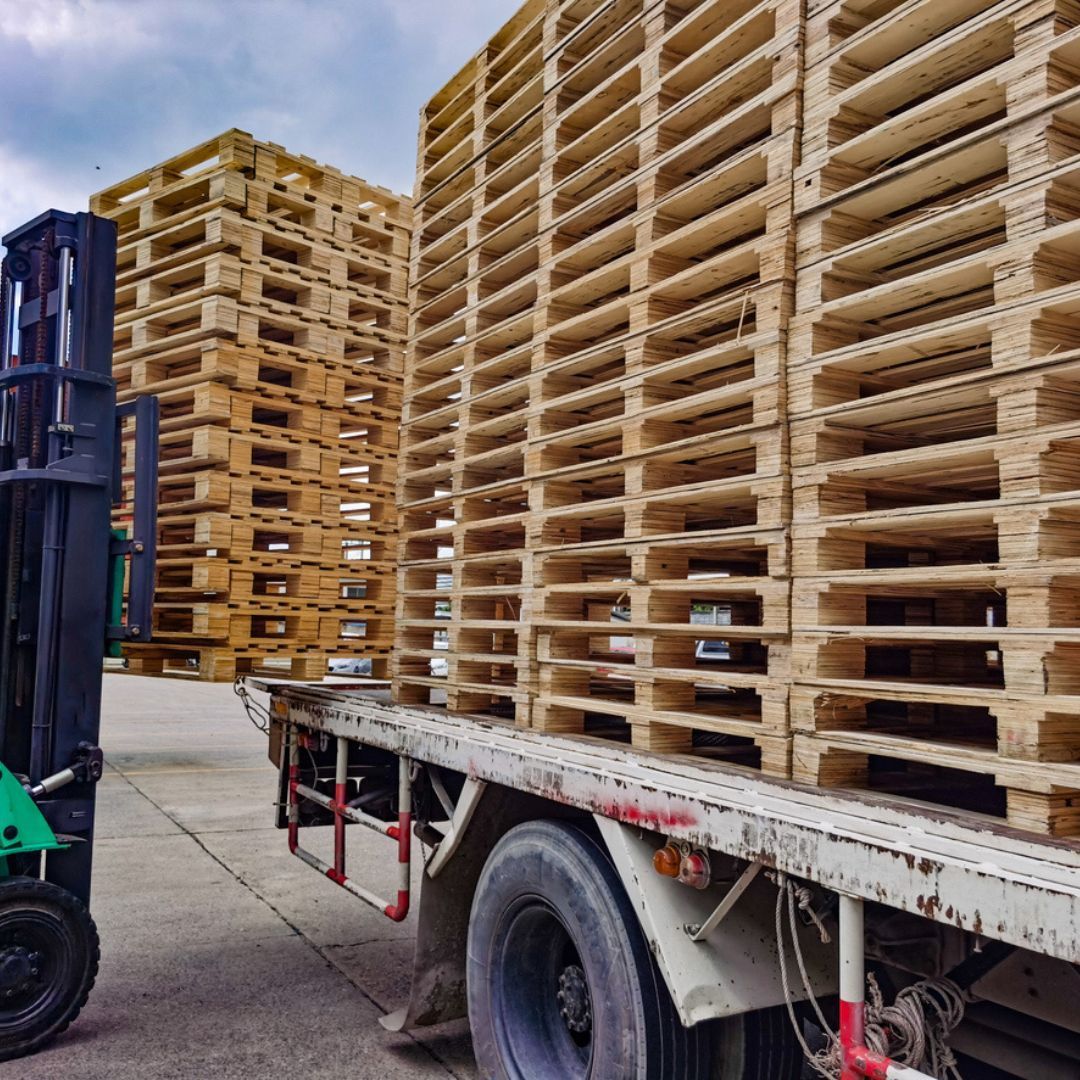 A forklift is loading wooden pallets onto a truck.