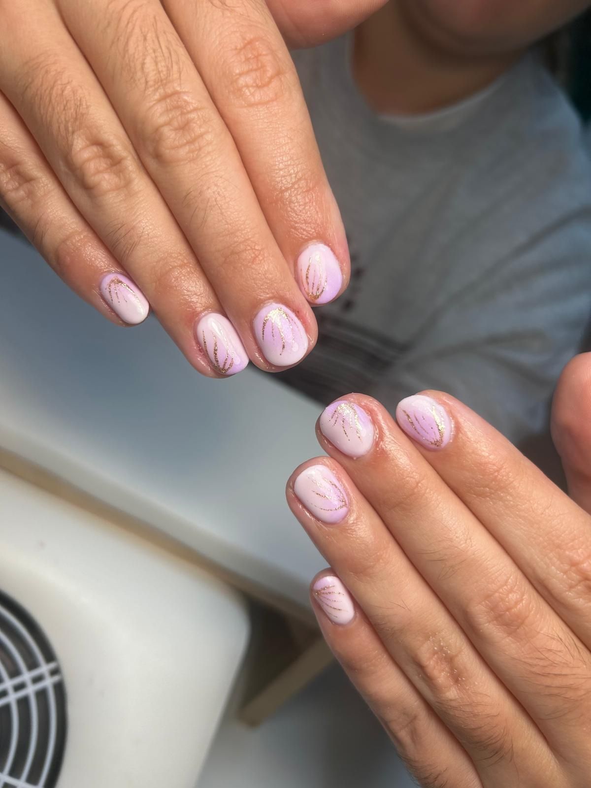 Manos con uñas cortas de color rosa claro, acentuadas con delicadas rayas moradas.