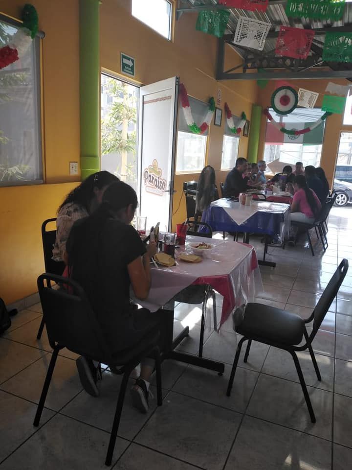 Patrons seated at tables in a brightly lit restaurant decorated with festive, colorful paper banners.