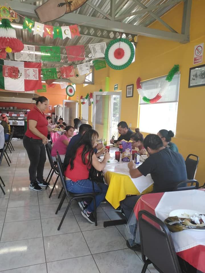 People eating lunch in a restaurant decorated with Mexican flag-themed streamers and paper cutouts.