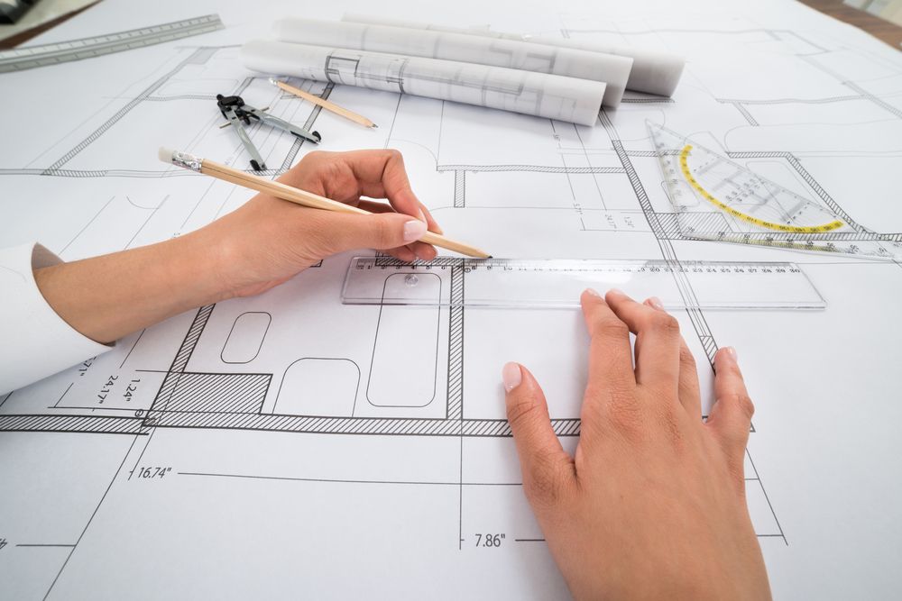 Hands Sketching Architectural Plans With Pencil and Ruler — Mid North Coast Drafting & Construction in Wingham, NSW
