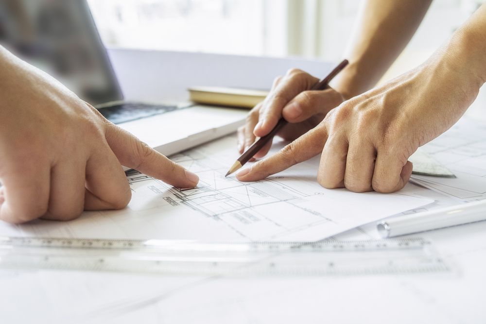 Hands Pointing at Architectural Blueprints, Collaborating on a Design — Mid North Coast Drafting & Construction in Forster, NSW