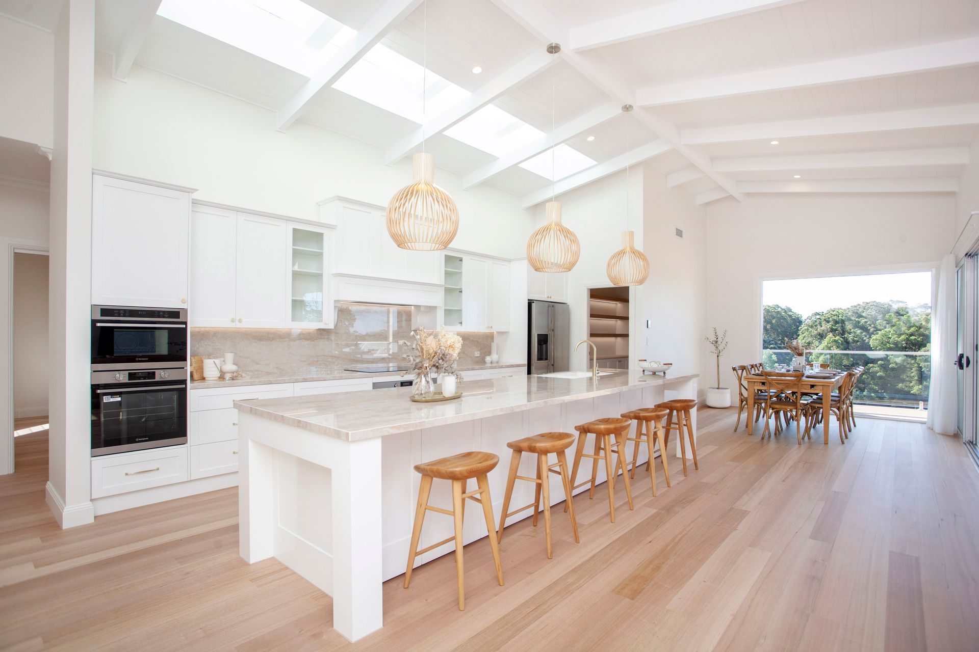 Bright White Kitchen With a Large Island, Wood Floors, and Skylights — Mid North Coast Drafting & Construction in Harrington, NSW