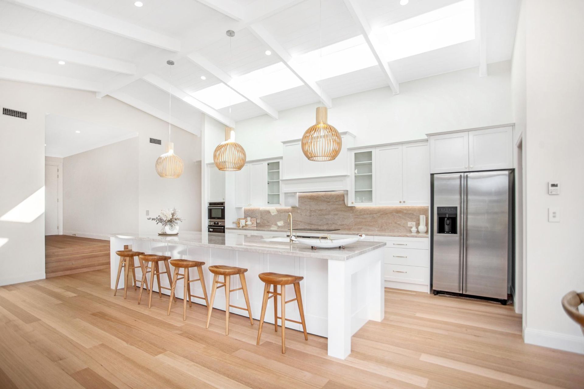 Spacious White Kitchen With Island, Skylights, and Stainless Refrigerator — Mid North Coast Drafting & Construction in Taree, NSW