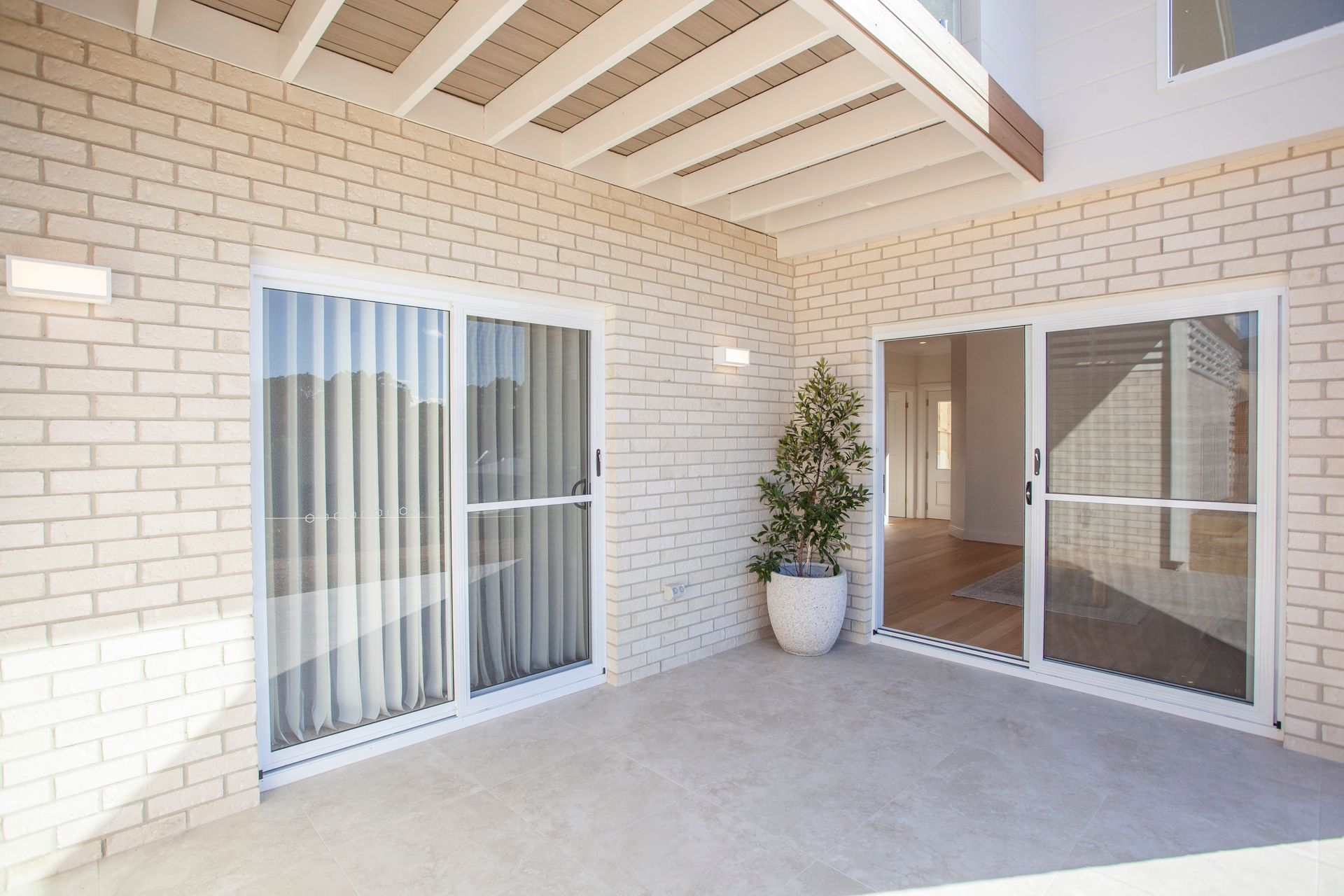 Covered Patio With Brick Walls, White Sliding Doors, and a Potted Plant — Mid North Coast Drafting & Construction in Nabiac, NSW