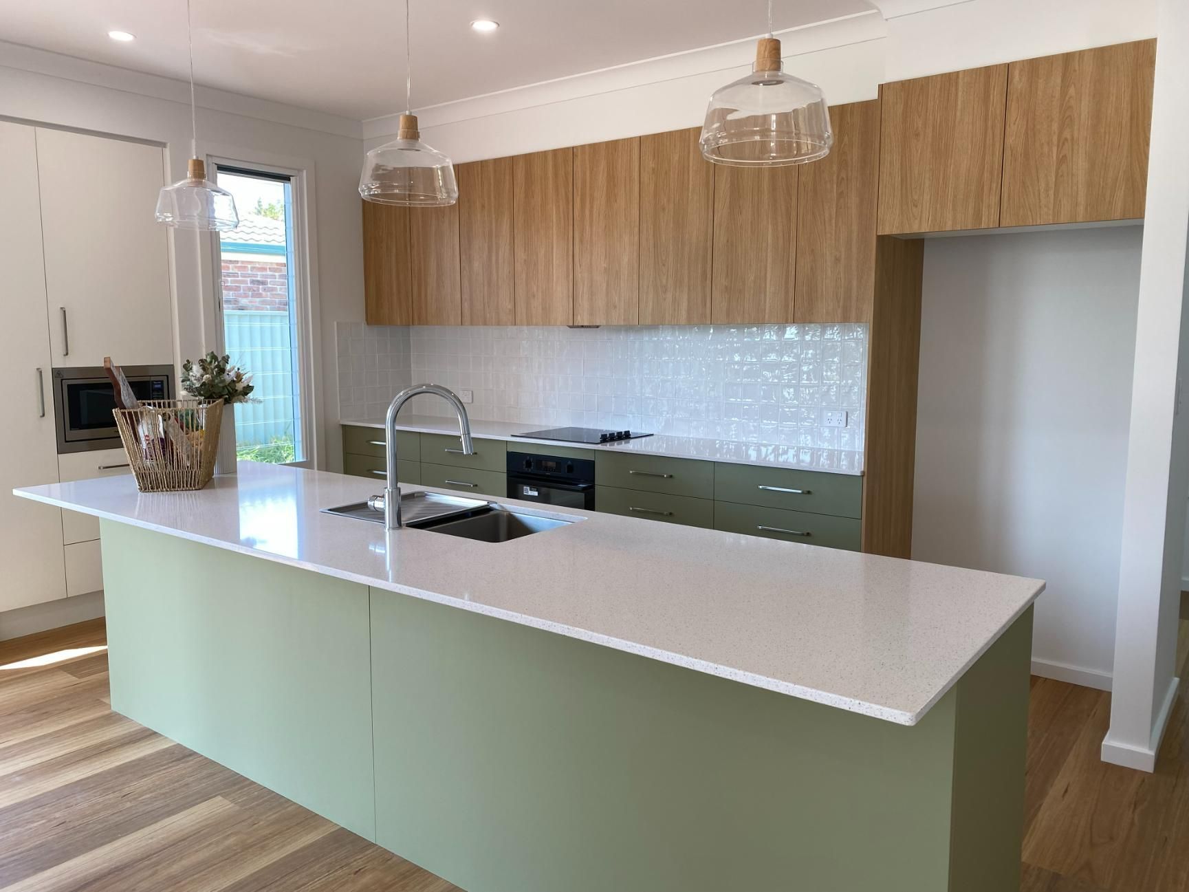 Modern Kitchen With Green Island, Wood Cabinets, and Pendant Lights — Mid North Coast Drafting & Construction in Taree, NSW