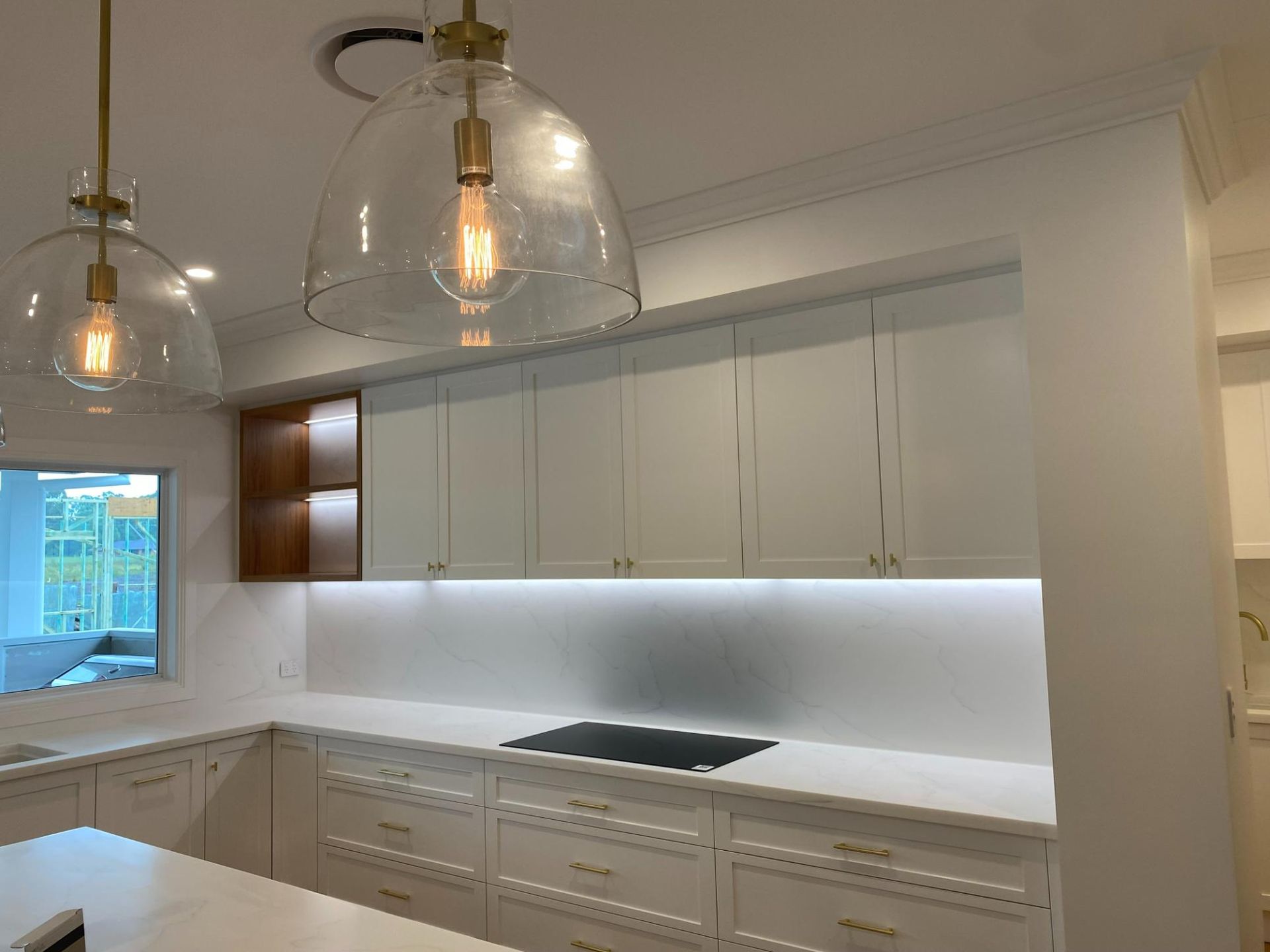 Modern White Kitchen With Overhead Cabinets and Pendant Lights — Mid North Coast Drafting & Construction in Taree, NSW