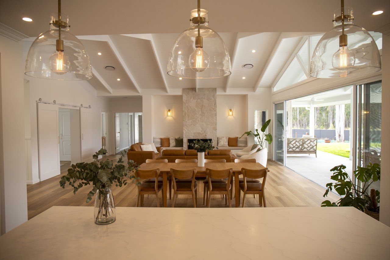 Spacious Dining Room With Wooden Table, Fireplace, and Outdoor Access — Mid North Coast Drafting & Construction in Taree, NSW