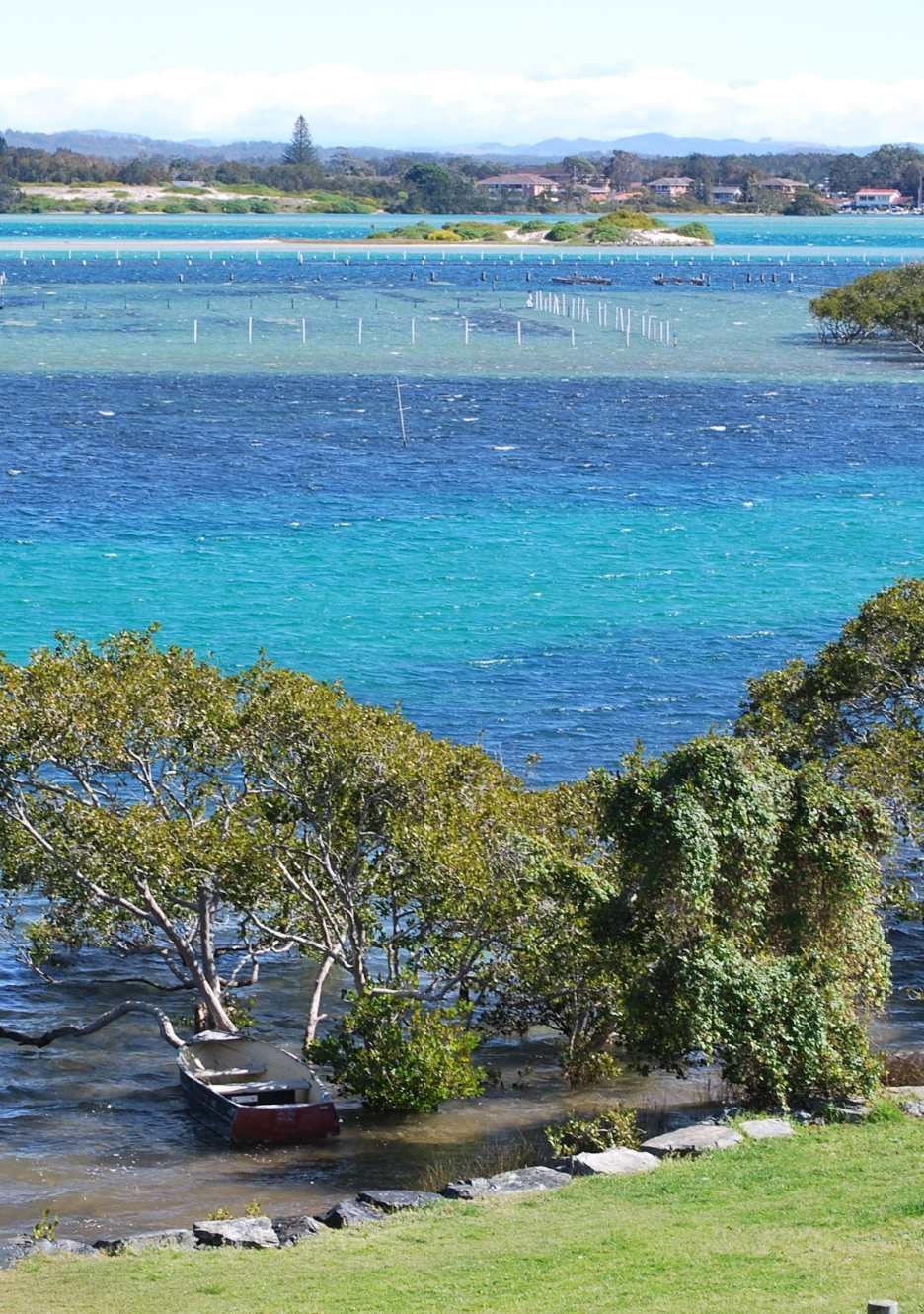 Small Boat in Turquoise Water With Lake and Green Land — Mid North Coast Drafting & Construction in Forster, NSW