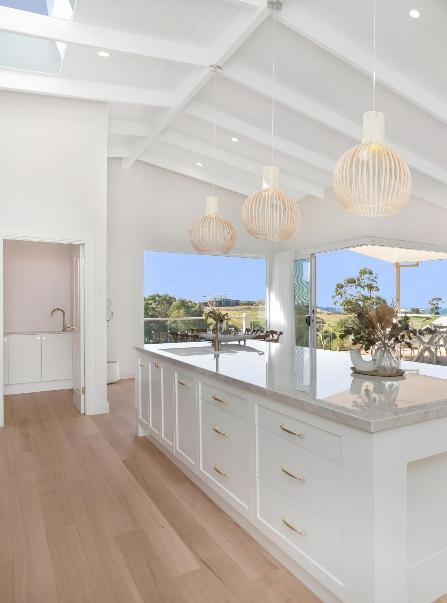 White Kitchen With Island, Wood Floors, and Ocean View — Mid North Coast Drafting & Construction in Forster, NSW