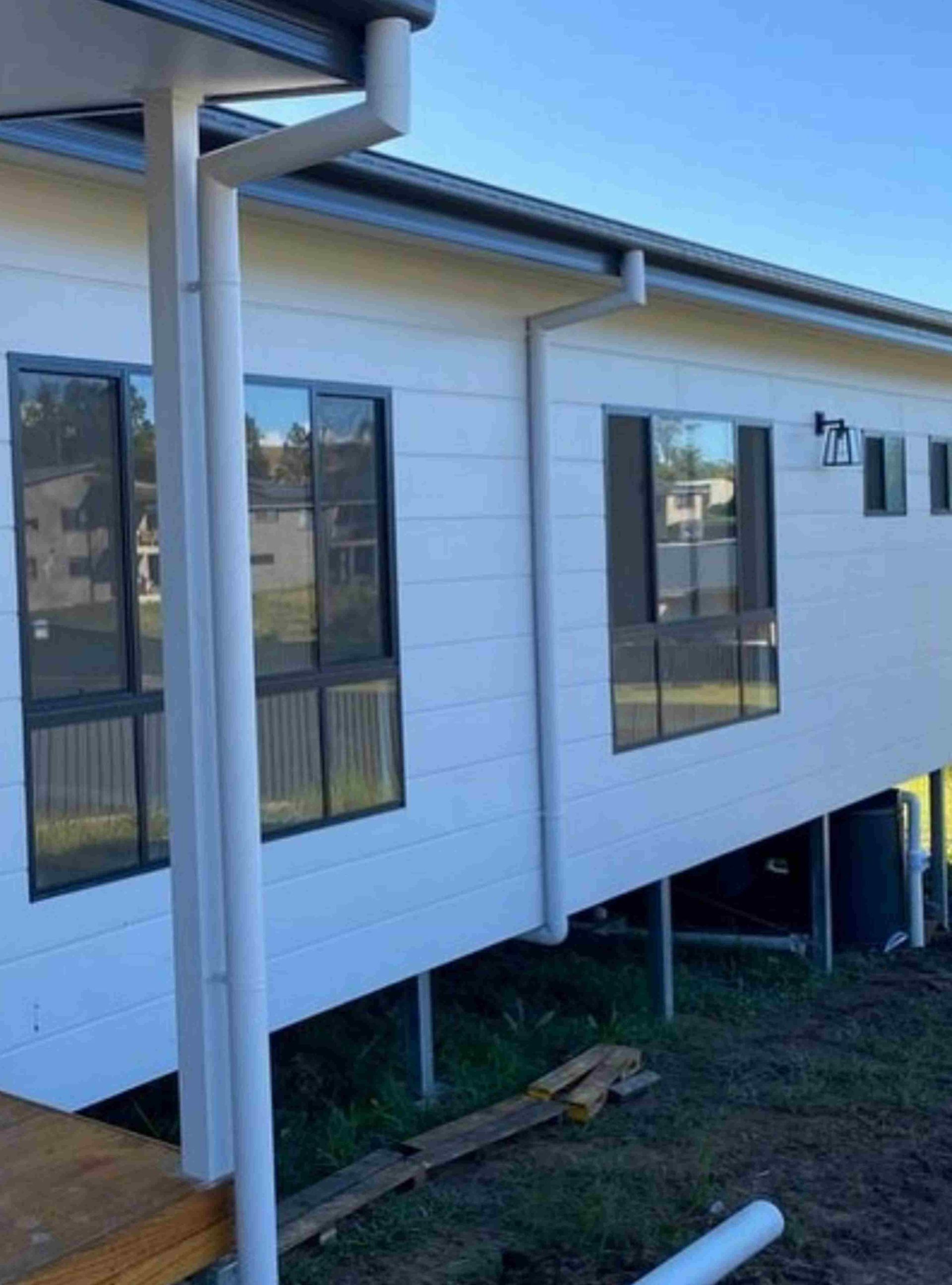 White House With Dark Window Frames Elevated on Stilts — Mid North Coast Drafting & Construction in Taree, NSW