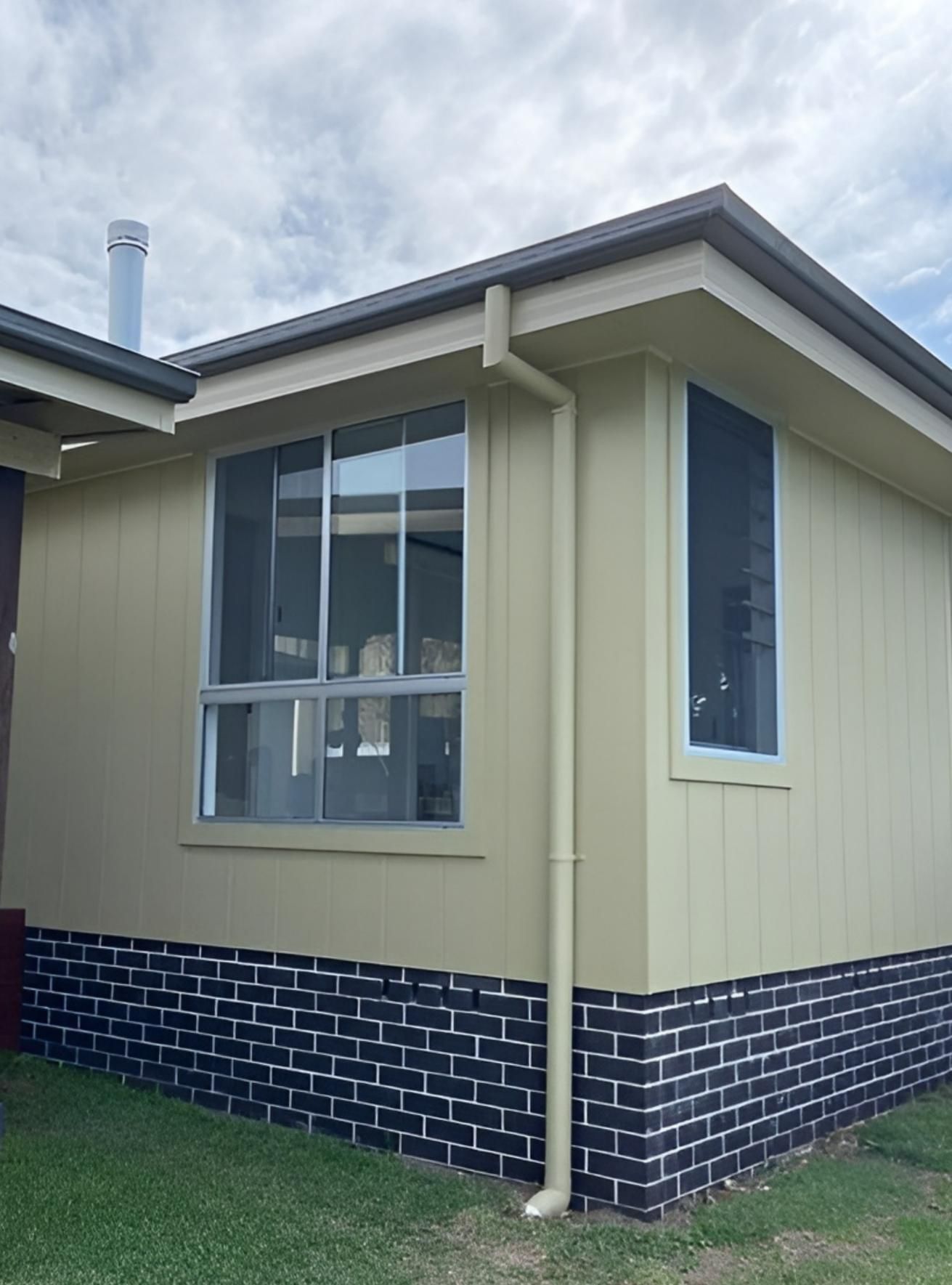 House Exterior With Tan Siding, Dark Brick Base, and Large Window — Mid North Coast Drafting & Construction in Taree, NSW