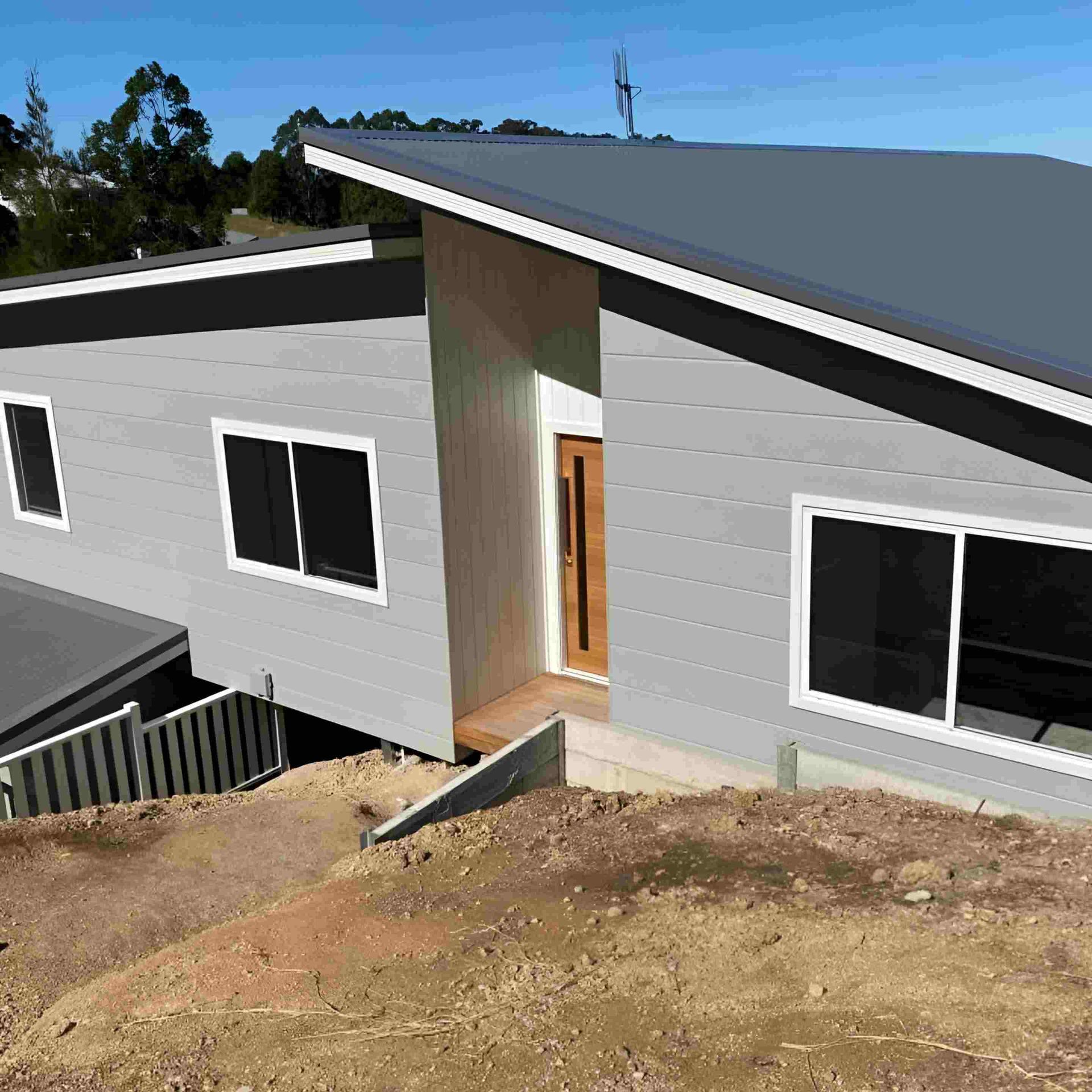 Modern Gray House With Angled Roof and Wooden Door — Mid North Coast Drafting & Construction in Taree, NSW