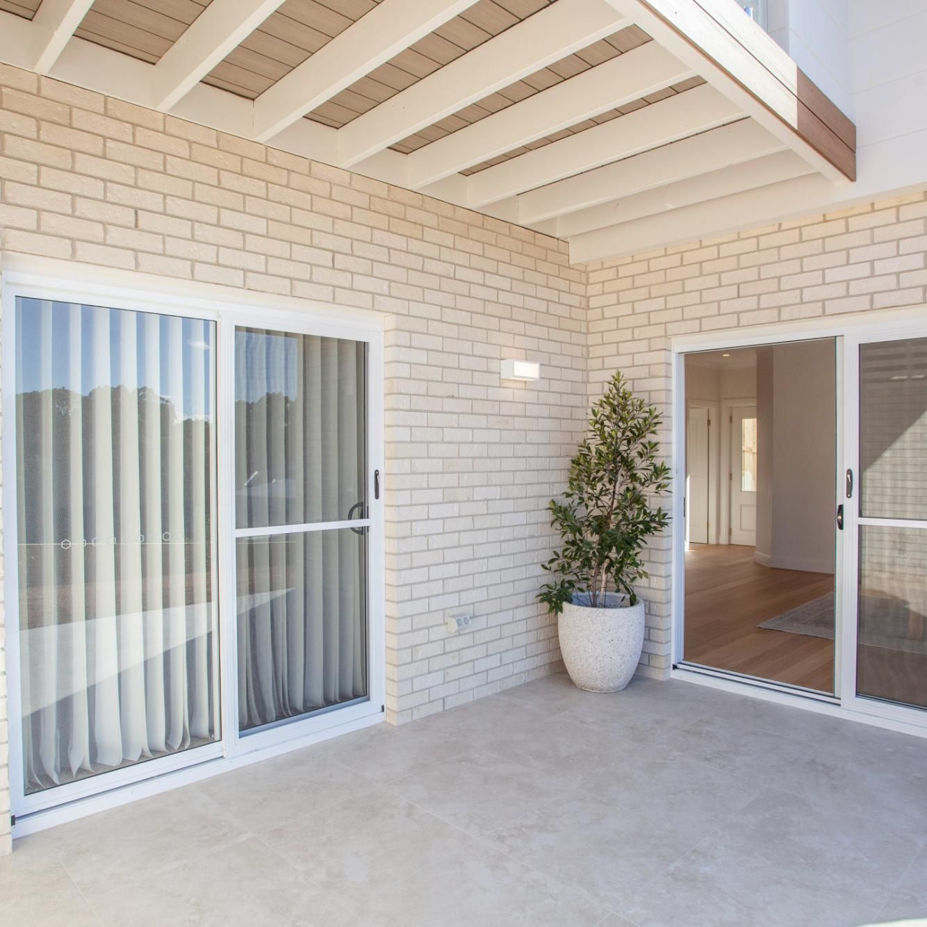 Patio With White Brick Walls, Sliding Glass Doors, and Potted Plant — Mid North Coast Drafting & Construction in Taree, NSW