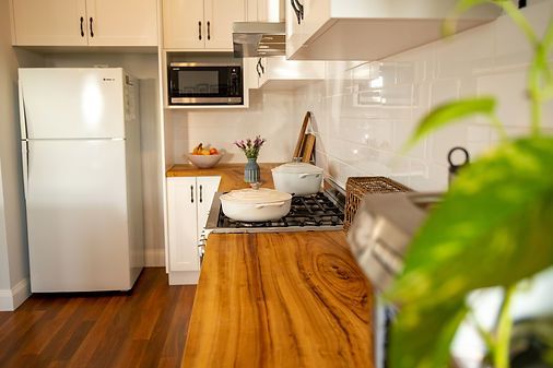 Cozy White Kitchen With Wooden Counters and Stainless Appliances — Mid North Coast Drafting & Construction in Taree, NSW