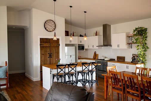 Open-Concept Kitchen With White Cabinets, Island, and Dining Table — Mid North Coast Drafting & Construction in Taree, NSW