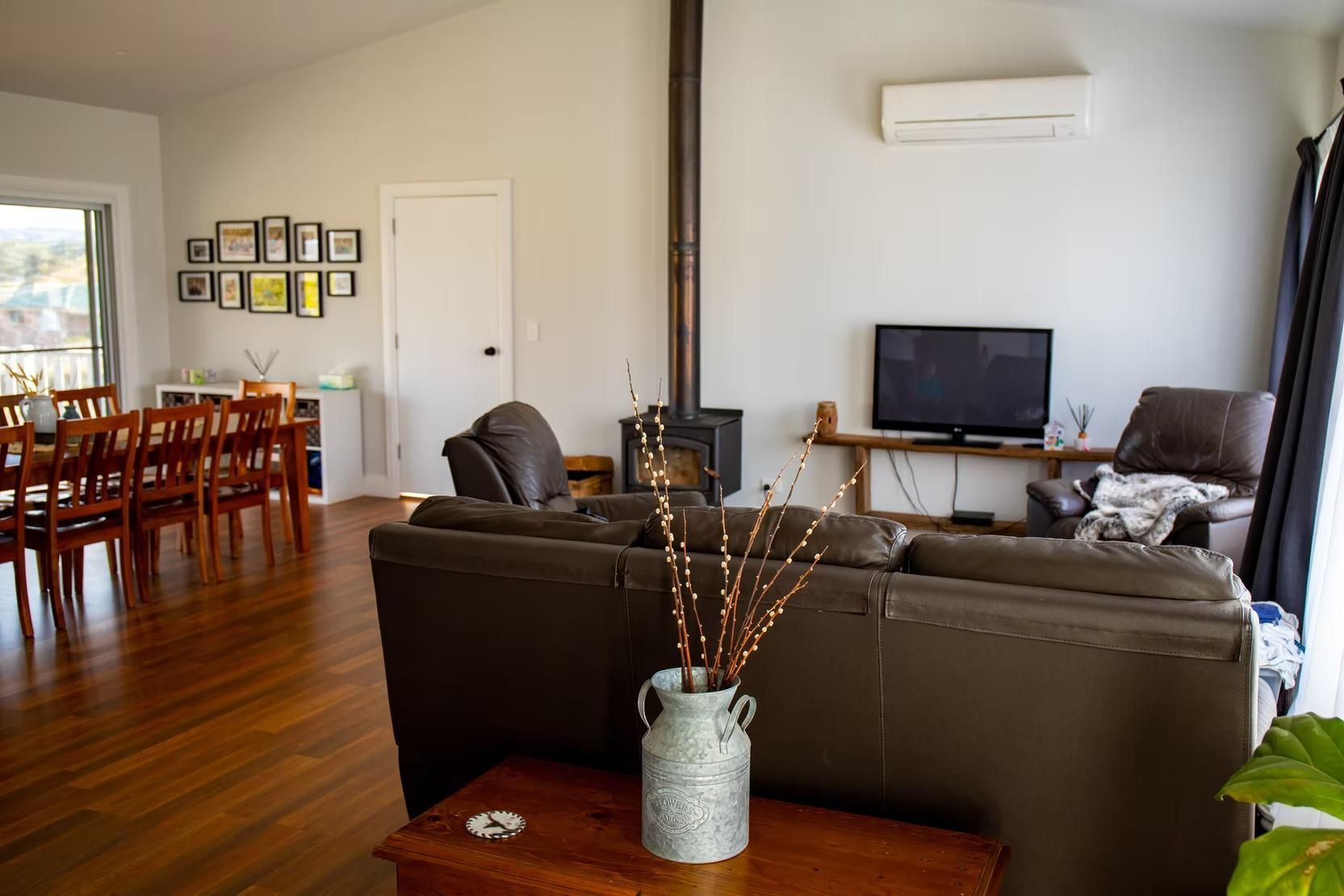 Living Room With Dark Leather Couch, Fireplace, and Dining Area — Mid North Coast Drafting & Construction in Taree, NSW
