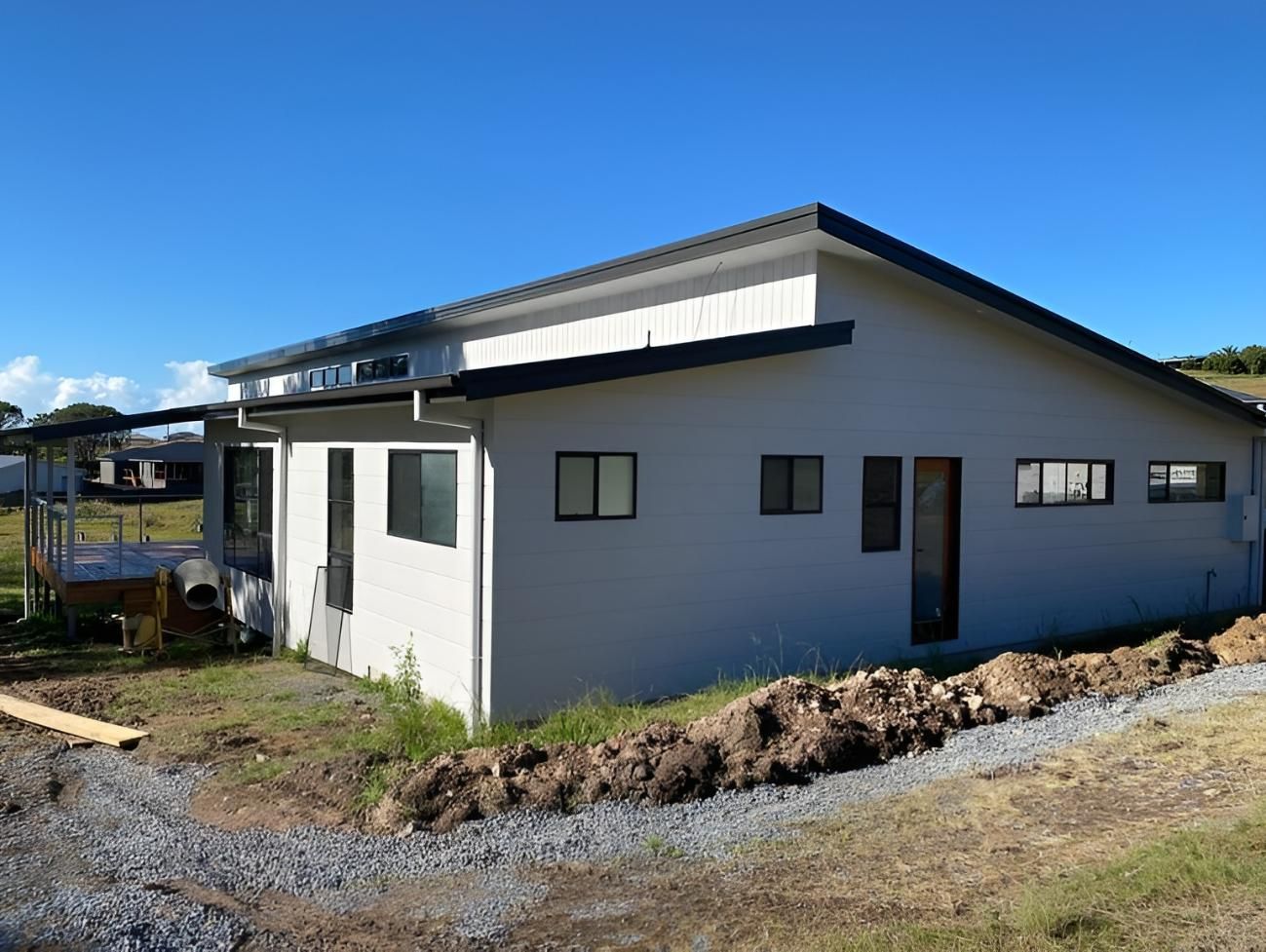 Modern White House With Black Trim on Grassy Hillside — Mid North Coast Drafting & Construction in Forster, NSW