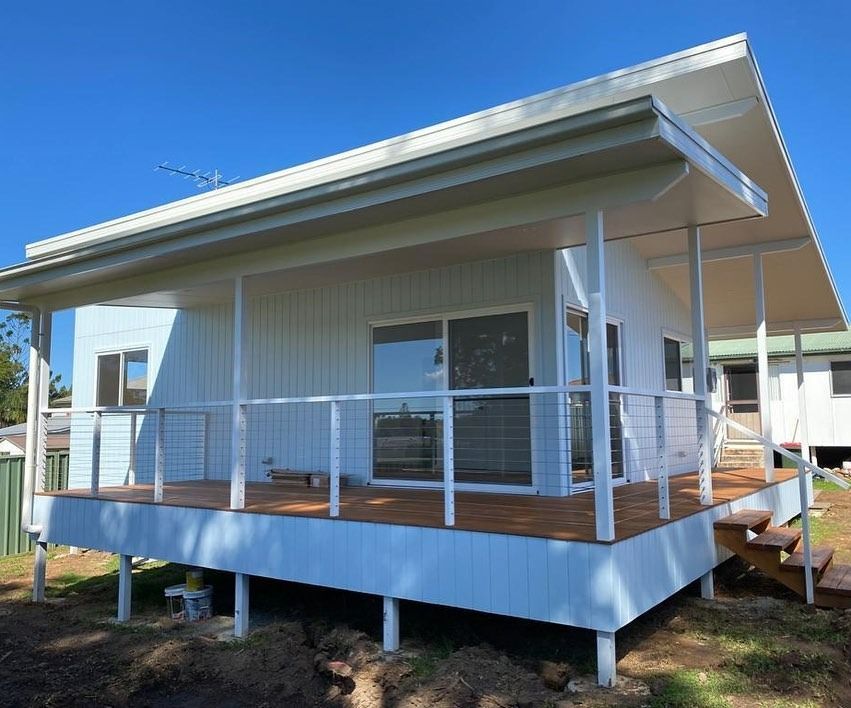 White Beach House With Deck, Railing, and Wooden Steps — Mid North Coast Drafting & Construction in Old Bar, NSW