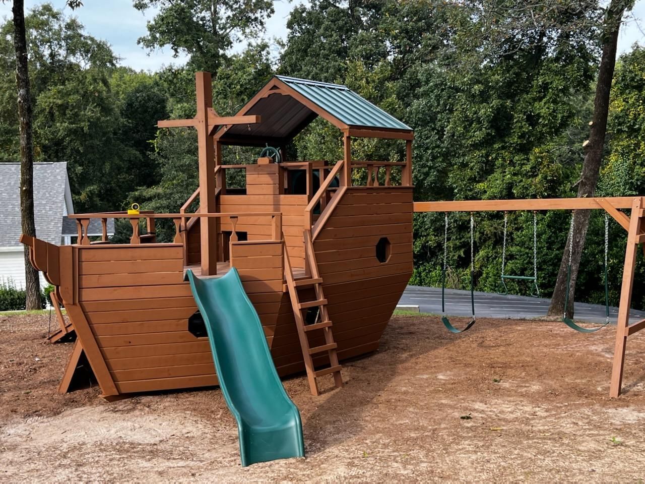 A playground set with a slide and swings in a backyard.