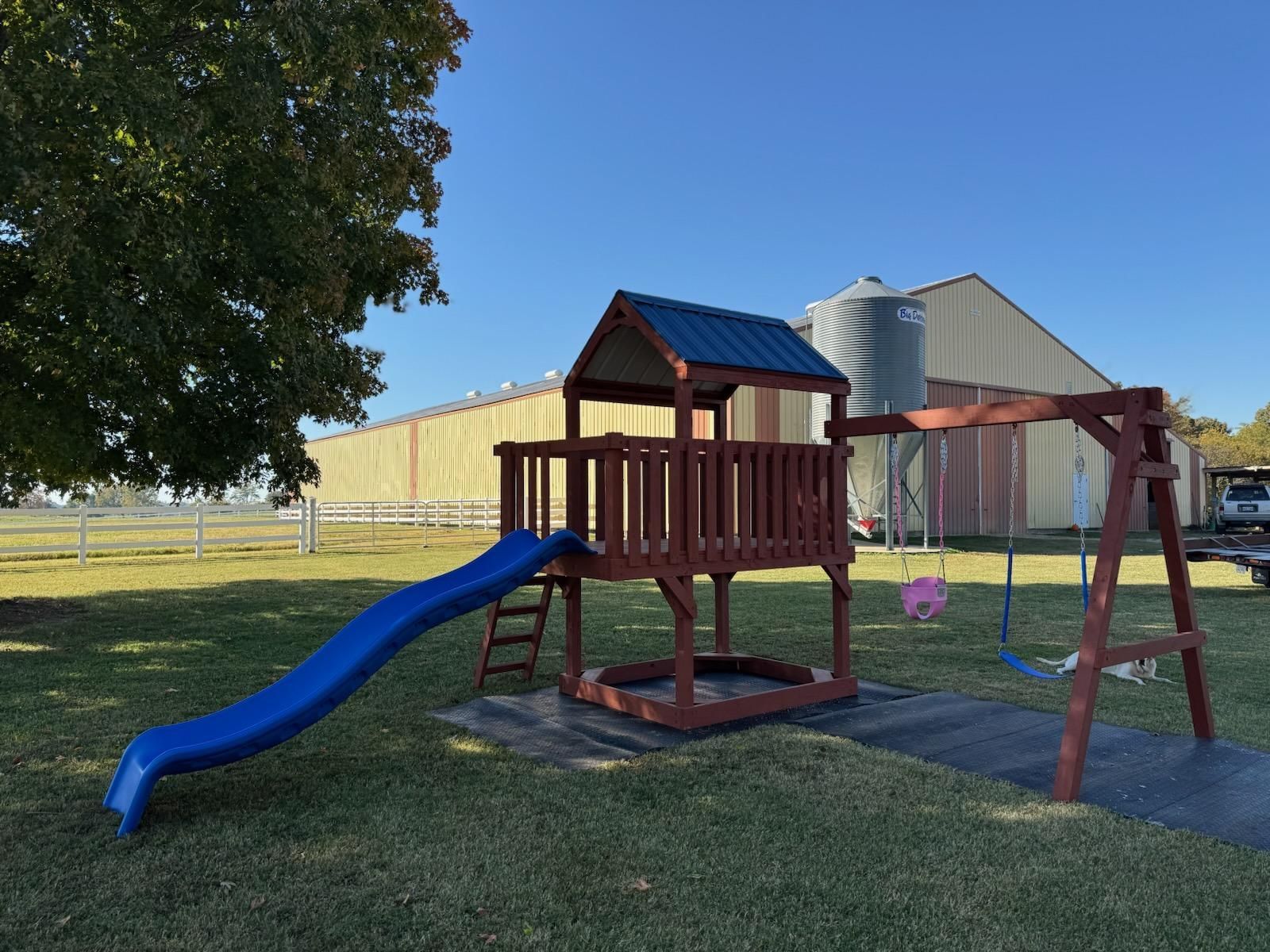 A playground set with a slide and swings in a backyard.