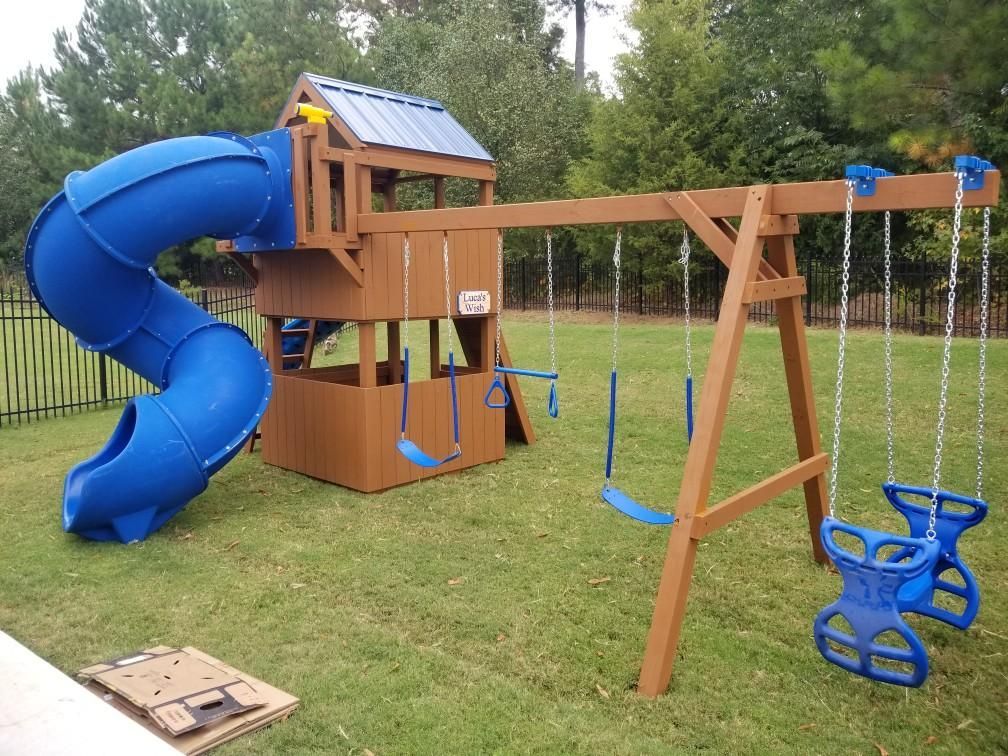 Brown wooden playset with a blue spiral slide, a swing set, and a playhouse structure.